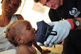 Bombero de BUSF prestando ayuda humanitaria a un niño durante el terremoto de Haití.